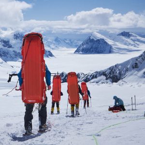 Mountaineers with sledge on his back coming down on Denali after burying extra stuff.